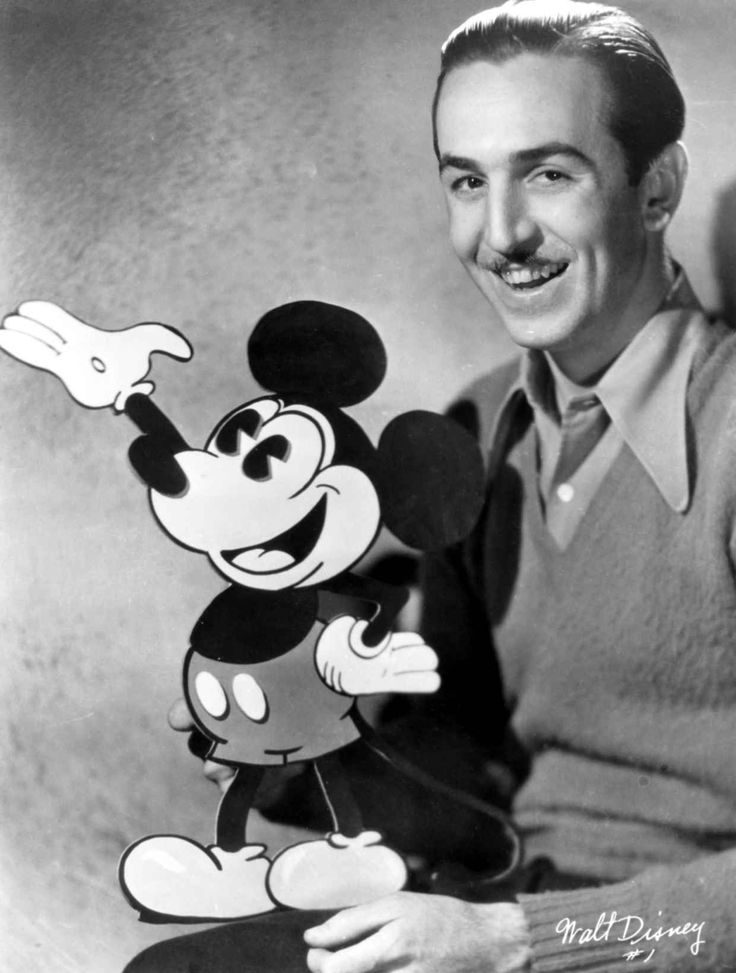 a man standing next to a cartoon mickey mouse