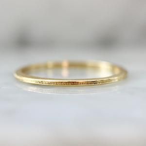 a yellow gold wedding band on a white surface