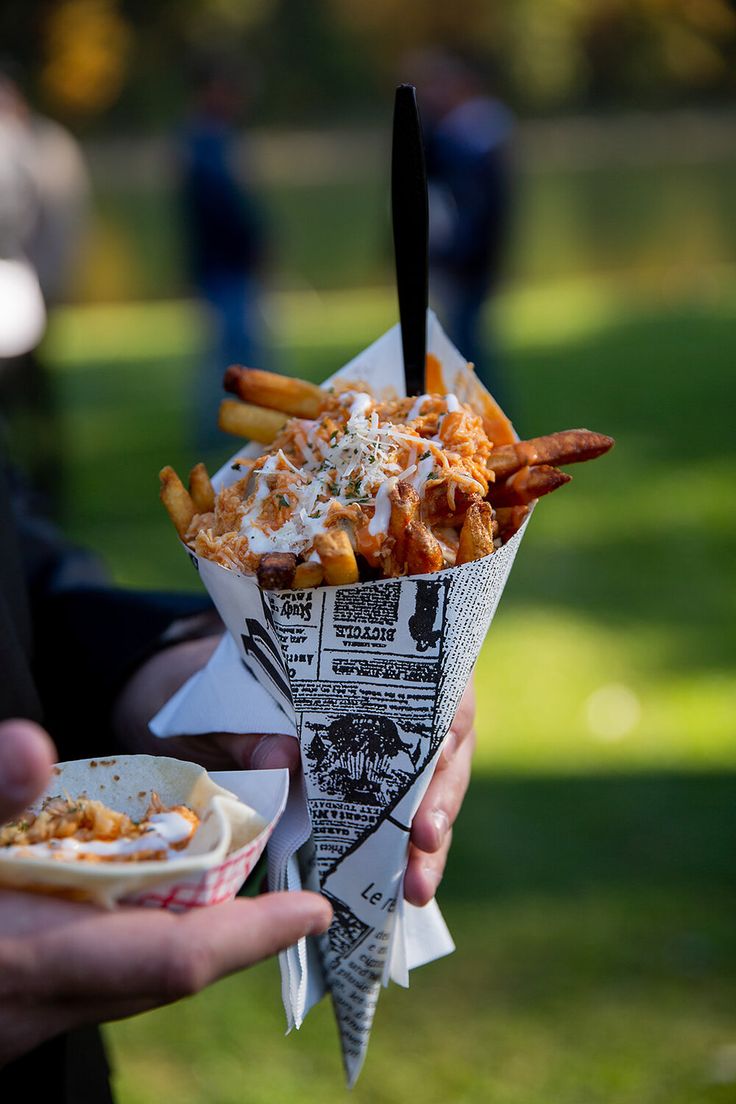 a person holding a paper plate with french fries and coleslaw on it in their hand