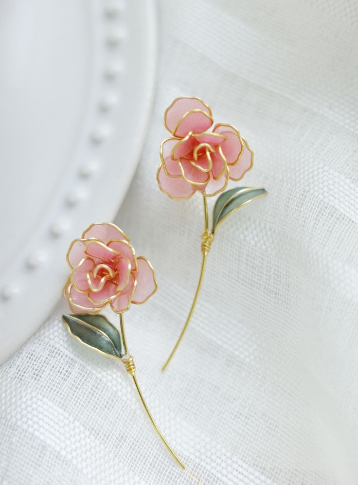 two pink flowers are sitting on a white surface