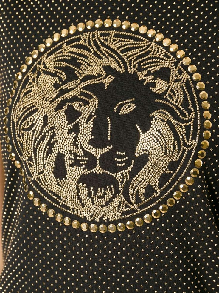 a woman wearing a black and gold top with a lion design on the chestline