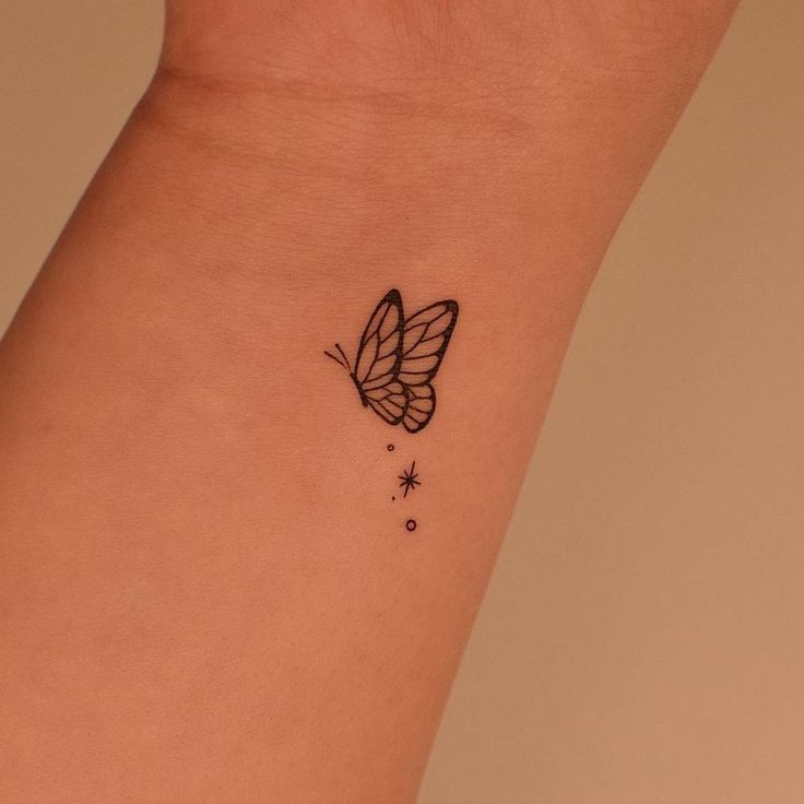 a small butterfly tattoo on the wrist is shown in black and white ink with stars around it