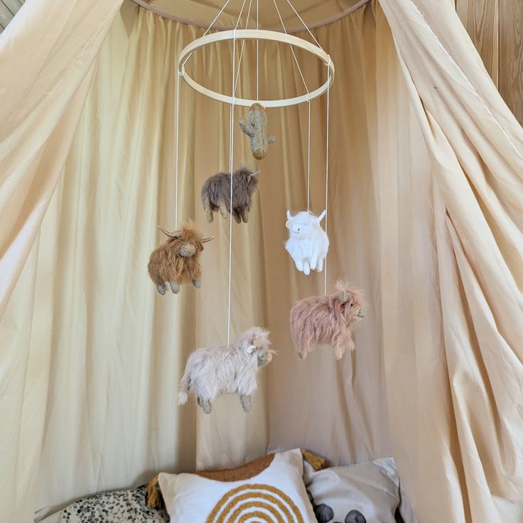 a canopy bed with several stuffed animals hanging from it's sides and pillows on the floor