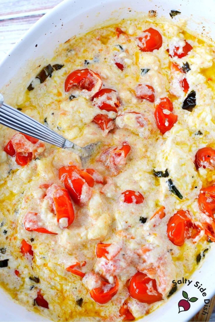 an omelet with tomatoes and other toppings in a white casserole dish