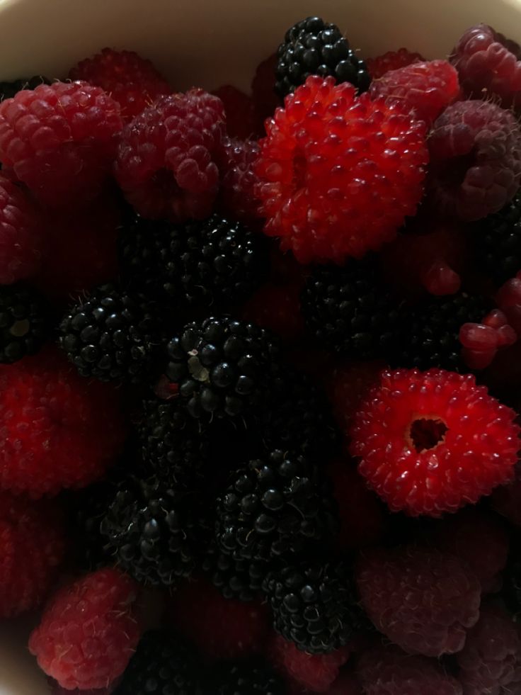 raspberries and blackberries in a white bowl