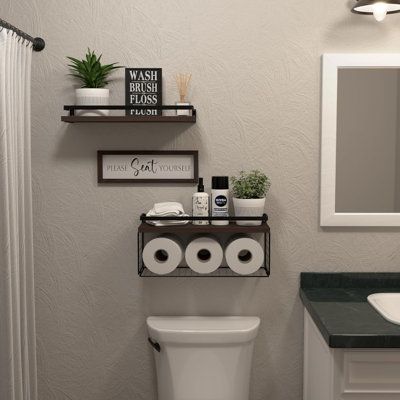 a white toilet sitting next to a bathroom sink under a mirror above a wooden shelf