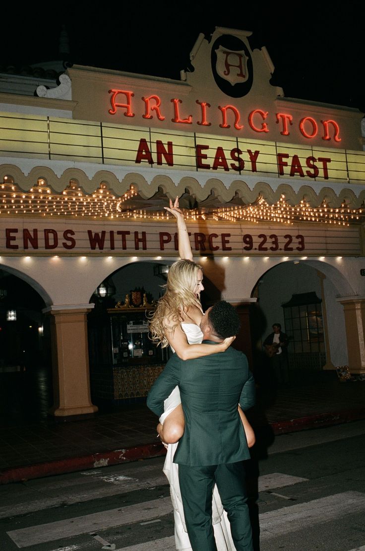 a man and woman standing in front of a theater