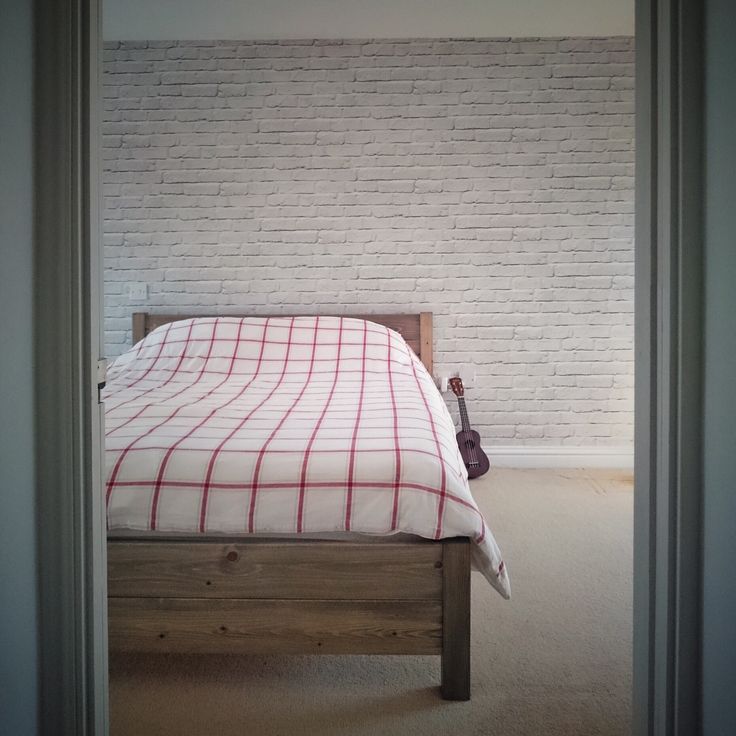 a bed with a red and white checkered bedspread in a bedroom next to a brick wall