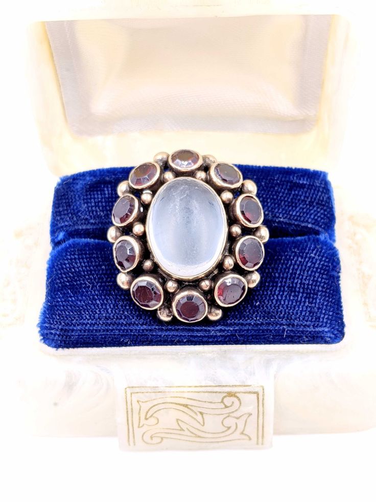 "Antique Moonstone Ring, Victorian 14k Gold Moonstone Garnet Ring, Georgian Large Oval Moonstone Garnet Ring, Garnet Moonstone Cluster Ring in a size 6 and sizable. An amazing huge Antique 14k Gold statement ring with a large center genuine Moonstone that is approximately 13.5ctw & measures 16mm x 12mm surrounded by 10 round genuine Garnet gemstones that are approximately 6.5ctw & 5mm diameter each. Total gemstone weight of 20ctw of Antique genuine gemstones in this fabulous ring! The ge White Oval Ruby Ring, Oval White Ruby Ring, Antique Oval Moonstone Ring Hallmarked, Antique Moonstone Ring, Oval Cabochon, Antique Moonstone Oval Cabochon Ring, Antique Oval Cabochon Moonstone Ring, Antique Oval Moonstone Ring, Antique Oval Hallmarked Moonstone Ring, Oval Opal And Moonstone Multi-stone Ring