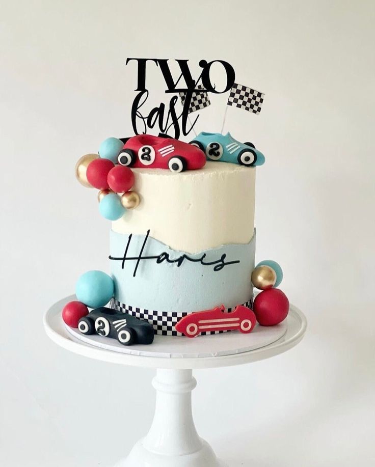 a two tiered cake with cars on it and the words two car happy birthday written on top