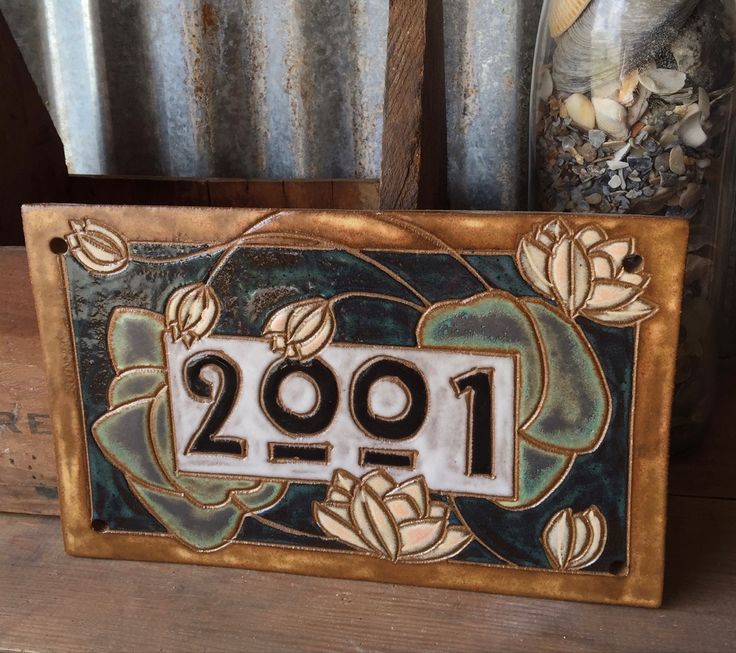 a metal plaque with the number twenty one in front of it and flowers on top