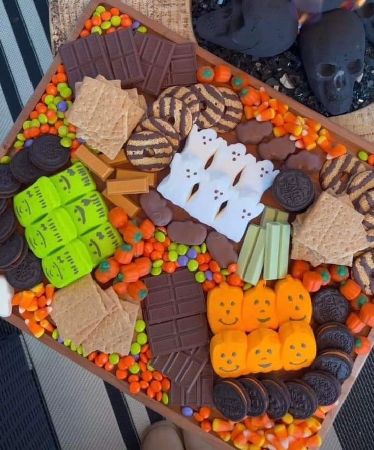 a tray filled with halloween treats on top of a wooden table covered in candy and candies