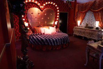 a heart shaped bed in a bedroom with lights on the headboard and foot board