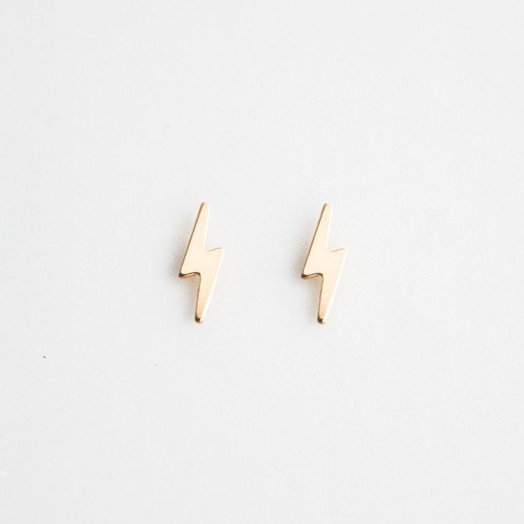 pair of gold earrings with lightning bolt design on them, against a plain white background