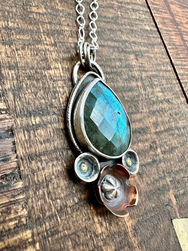 Labradorite is a beauty of a gem! It’s iridescent colors are amazing. It’s no wonder it’s know for sparking creativity! This mixed metal piece feature hand formed flowers of copper and silver with brass adornments. This little beauty is 1” wide and almost 2” total length, it comes on a 20”sterling silver necklace. Spiritual Silver Jewelry With Patina, Iridescent Unique Jewelry, Iridescent Unique Metal Jewelry, Unique Sterling Silver Jewelry With Patina, Unique Iridescent Jewelry With Natural Stones, Artisan Iridescent Gemstone Jewelry, Artisan Iridescent Jewelry For Jewelry Making, Unique Flower-shaped Metal Jewelry, Unique Flower Shaped Metal Jewelry