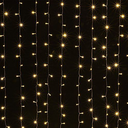 white string lights are hanging from the side of a wall in front of a black background