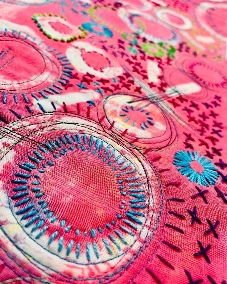 close up view of pink and blue fabric with circular designs on the top, in full color