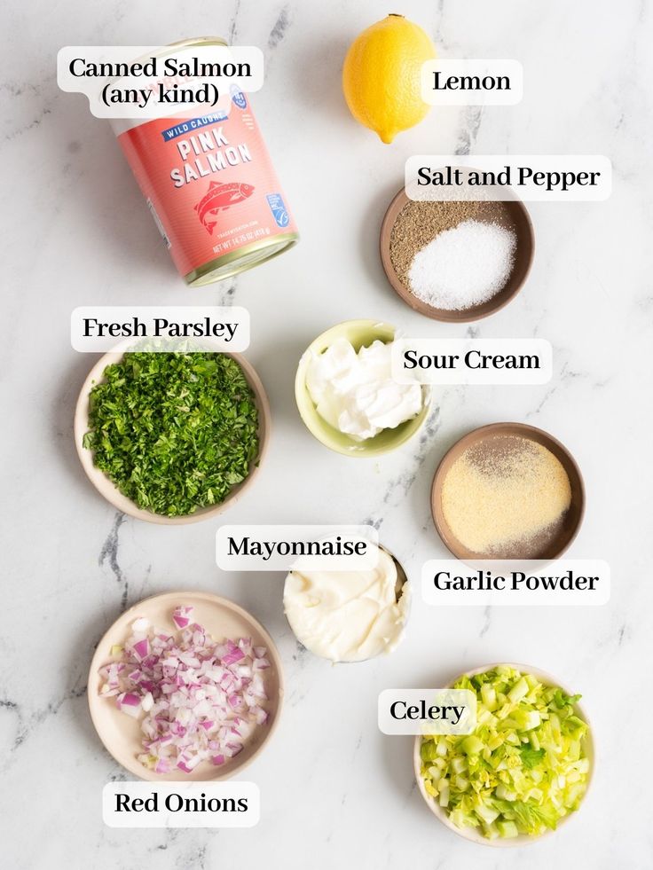 the ingredients for this recipe are shown in bowls on a marble countertop, including lemons, mayonnaise, sour cream, garlic powder, and celery