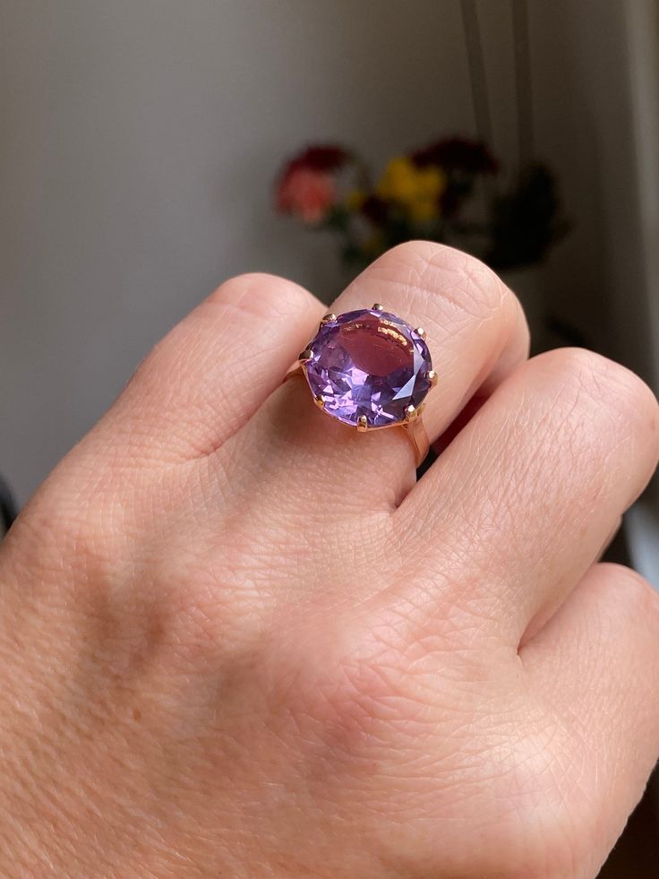 A huge 6 carat amethyst sits in a basket setting of 18k rose gold. This ring is truly a show stopper! The amethyst is synthetic (meaning created in a lab rather than in nature) and sparkles with light purple and blue undertones.  Details: Metal Purity -18k yellow gold (professionally acid tested to confirm) Ring size - 7.5 Weight - 5.3g Amethyst size - 14 mm diameter, 6 carats Ring Rise off of finger - 7.64 mm If this isn't your size, you are welcome to have it sized on your own, OR we can have Luxury Rose Gold Amethyst Ring With Center Stone, Luxury Rose Gold Amethyst Ring, Elegant Rose Gold Amethyst Ring With Center Stone, 14k Gold Brilliant Cut Purple Amethyst Ring, Classic Rose Gold Amethyst Rings, Formal Rose Gold Amethyst Ring With Center Stone, Formal Rose Gold Amethyst Ring, Elegant Faceted Amethyst Ring In Yellow Gold, Luxury Solitaire Amethyst Ring