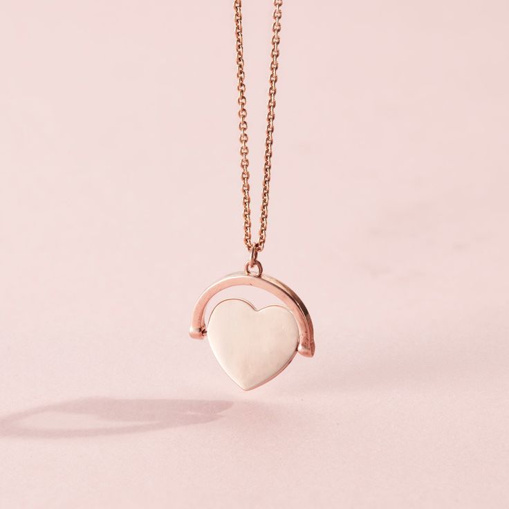 This gorgeous Heart Spinner Necklace is made from 18ct Rose Gold plated Sterling Silver. The design features a spinning heart pendant suspended from one of our classic trace chains.  The Spinning Necklace is reminiscent of traditional spinning necklaces with a modern luxe twist. Each necklace is handcrafted in our Brighton workshop from solid sterling silver then plated in 18ct Rose gold plate. Pendant measures approx 17. 2mm x 18. 3mm. Comes suspended on 18" chain. 18ct Rose Gold plated Sterlin Rose Gold Heart Pendant Necklace Fine Jewelry, Heart-shaped Rose Gold Charm Necklace With Chain, Rose Gold Heart Charm Fine Necklace, Rose Gold Heart Pendant Necklace Gift For Her, Fine Jewelry Rose Gold Necklace With Heart Charm, Rose Gold Fine Jewelry Necklaces With Heart Charm, Rose Gold Heart Pendant Necklace For Her, Minimalist Rose Gold Heart Cut Jewelry, Rose Gold Charm Necklace With Heart Pendant