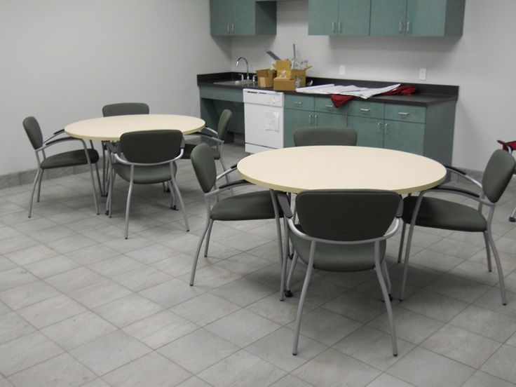 an empty room with several chairs and tables in the center, including one for four