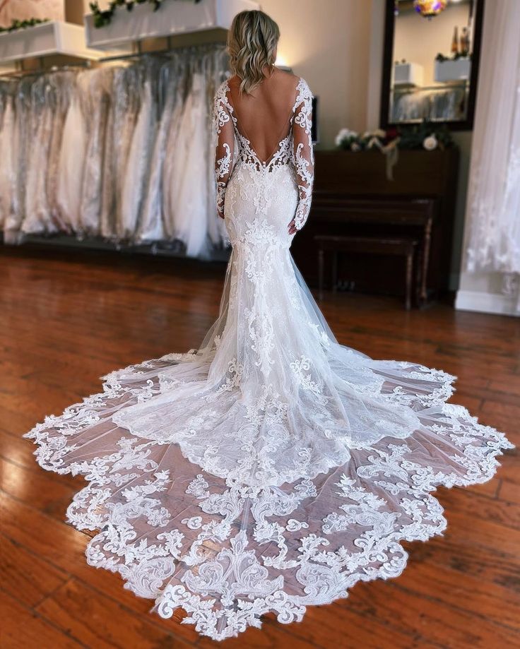 a woman in a white wedding dress standing on a wooden floor with her back to the camera