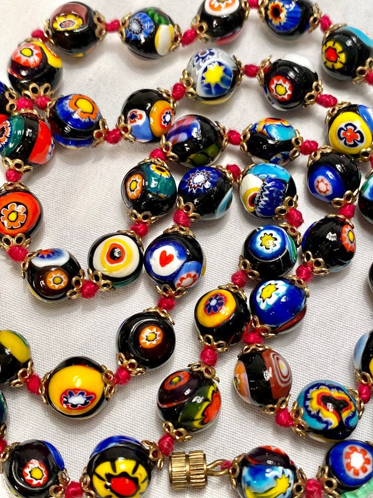 a multicolored beaded necklace is displayed on a white tablecloth with red, yellow, and blue beads