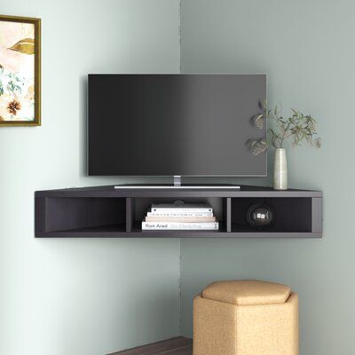 a flat screen tv mounted to the side of a wall next to a footstool