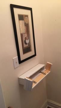 an empty toilet in a bathroom next to a painting on the wall and a framed picture above it