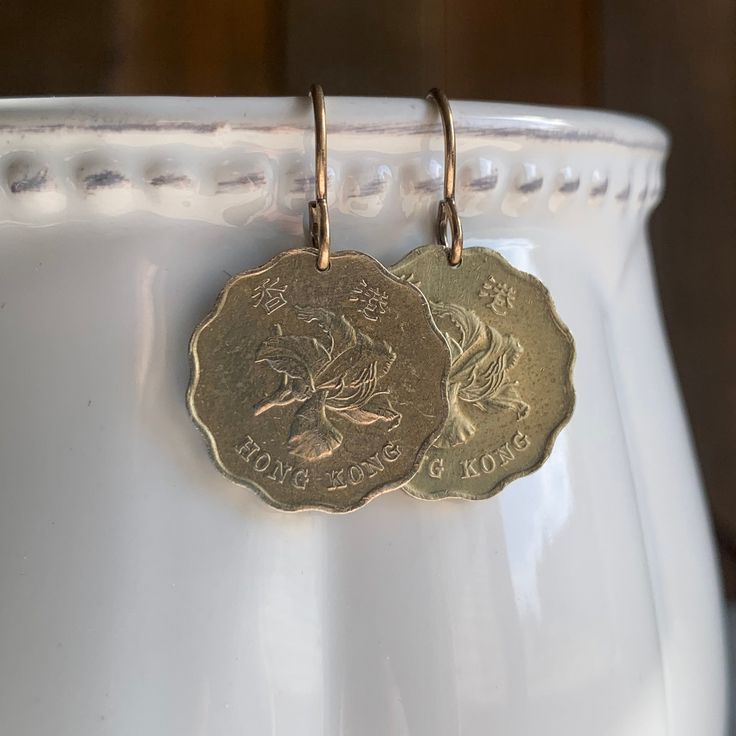 "Hong Kong Coin Earrings, Bauhinia Orchid, Scalloped Edge, Travel Souvenir, Wanderlust, Foreign Coin Jewelry, Brass --------------- Coin: 20 Cents Country: Hong Kong Dates: Minted from 1975-1998 There are two design options for this coin - but it is the scalloped edge that makes this coin unique and perfect as a simple disc earring slightly smaller than a penny. Polished to a bright shine and paired with copper ear wires, these are the perfect gift for anyone celebrating the Asian heritage or ce Souvenir Bags, Foreign Coins, Coin Design, Coin Pendant Necklace, Coin Earrings, Grand Rapids Mi, Disc Earrings, Travel Souvenirs, Coin Jewelry