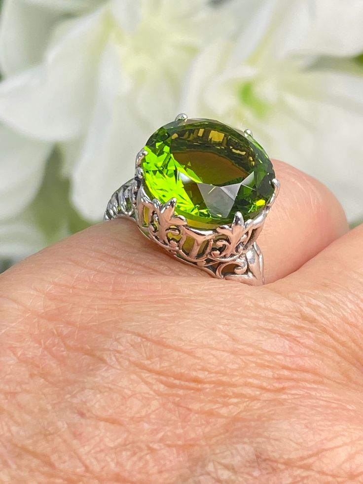 Peridot Sterling Silver RingKing Design#D123 This is a reproduction of a sterling silver Gothic filigree antique ring with a stunning 12 carat green peridot gemstone solitaire. This round cut simulated gem is 15mm in diameter. The inside of the band is marked 925 for sterling silver. Notice the beautiful intricate Gothic claw design of the silver filigree setting. The swirls echo down the band. This large round gemstone sits regally atop the fashionable setting. This stately ring garners attention and respect with its bold, arresting profile. Elegant Green Gemstones With Prong Setting, Classic Green Gemstone With Center Stone, Green Elegant Filigree Ring For Formal Occasions, Elegant Green Filigree Ring For Formal Occasions, Elegant Lime Green Jewelry With Center Stone, Elegant Lime Green Gemstone Rings, Exquisite Green Oval Ring, Exquisite Green Round Jewelry, Green Elegant Formal Filigree Ring