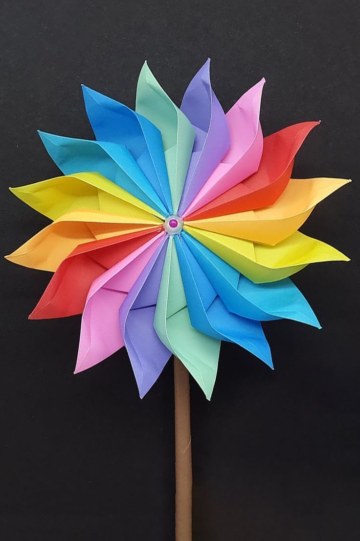 a multicolored pinwheel sitting on top of a wooden stick in front of a black wall