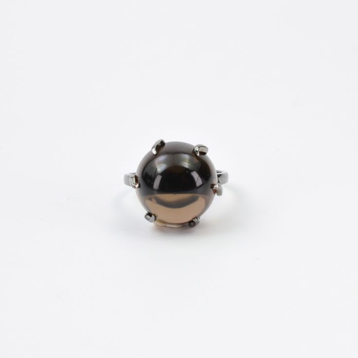 Embrace the ethereal allure of this Smokey Quartz ring, featuring a captivating round cabochon cut stone. The stone's mysterious smoky brown hue is perfectly highlighted by its smooth, dome-shaped surface, offering a mesmerizing play of light and shadow. Set in a sleek, minimalist prong setting, the stone sits elegantly atop a slender band, allowing the gemstone to be the focal point. This ring's design is a harmonious blend of simplicity and sophistication, making it a timeless piece that adds Classic Formal Cabochon Moonstone Ring, Timeless Domed Cabochon Rings, Formal Round Gemstone Cabochons, Vintage Oval Cabochon Moonstone Ring, Elegant Domed Moonstone Gemstone Ring, Vintage Moonstone Oval Cabochon Ring, Silver Heirloom Dome Ring, Round Shape, Elegant Domed Cabochons For Gifts, Heirloom Silver Dome Ring