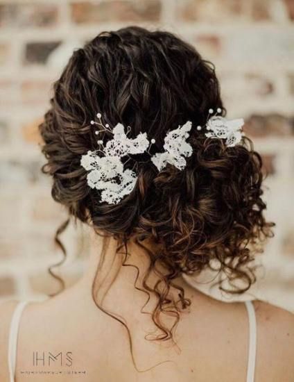 a woman with curly hair wearing a white flower comb