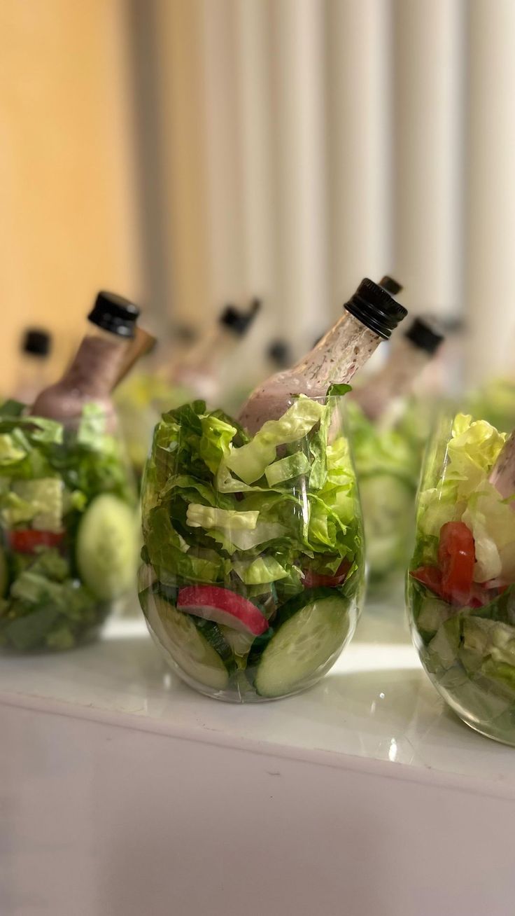 several jars filled with different types of salads on a white counter top next to each other