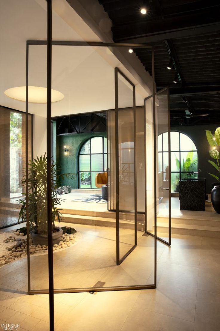 an empty room with glass partitions and plants in the corner on either side of the room