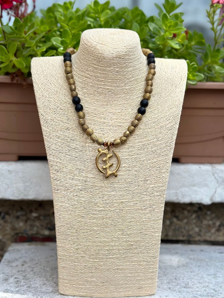 Go bold with this stunning African Gye Nyame  necklace for any occasion. Pendant made from recycled brass items using the ancient lost wax method.  Gye Nyame is one of Ghanaian Adinkra symbols meaning (Only God/Except God)  Paired with onyx gemstones for durability and comfort.  beads are approximately 12mm in diameter.  Necklace is approximately 27 inches long Gold Medallion Necklace In Copper, Gold Copper Medallion Necklace, Bronze Metal Necklace With Round Beads, Gold Antique Finish Copper Necklaces, Gold Copper Necklace With Antique Finish, Adjustable Medallion Necklace With Antique Finish, Antique Finish Medallion Necklaces, Bronze Medallion Necklace In Brass, Bronze Medallion Necklace With Spiritual Style