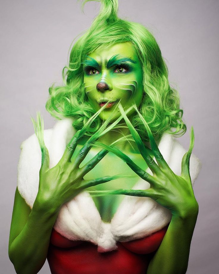 a woman with green hair and makeup is holding her hands up to her face while posing for the camera