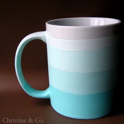 a blue and white coffee mug sitting on top of a brown table next to a black wall