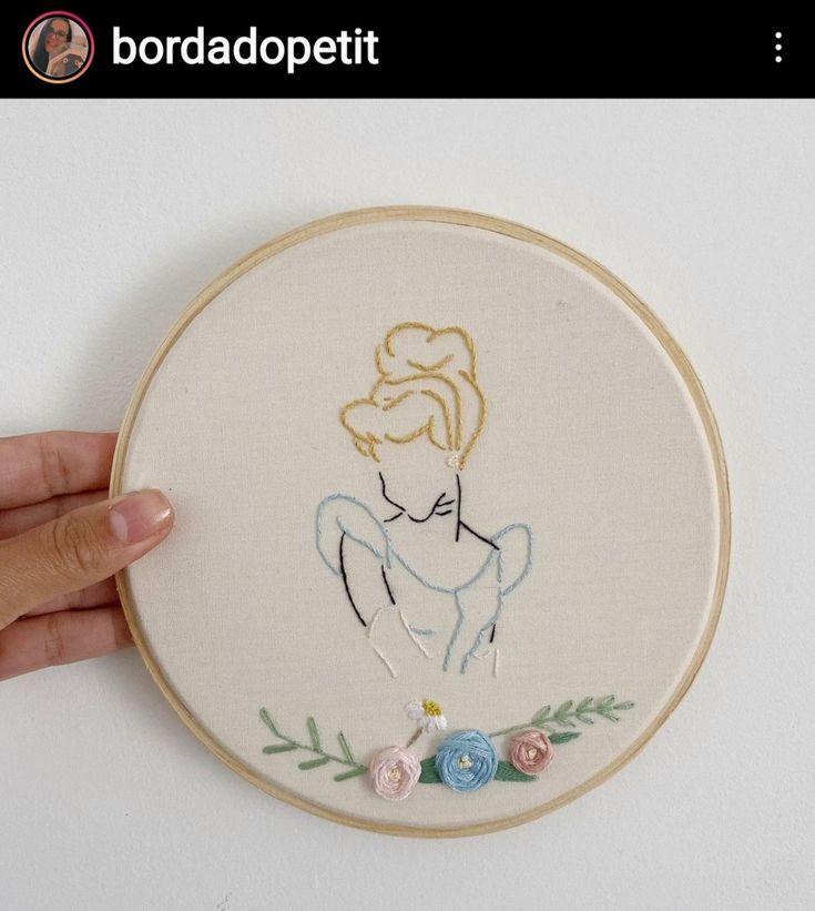 a hand is holding up a embroidery hoop