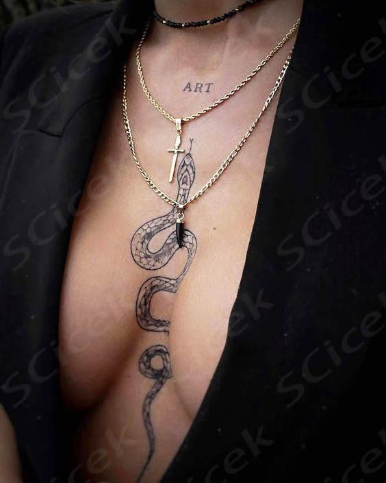 a woman with a snake tattoo on her chest is wearing a black blazer and gold chain