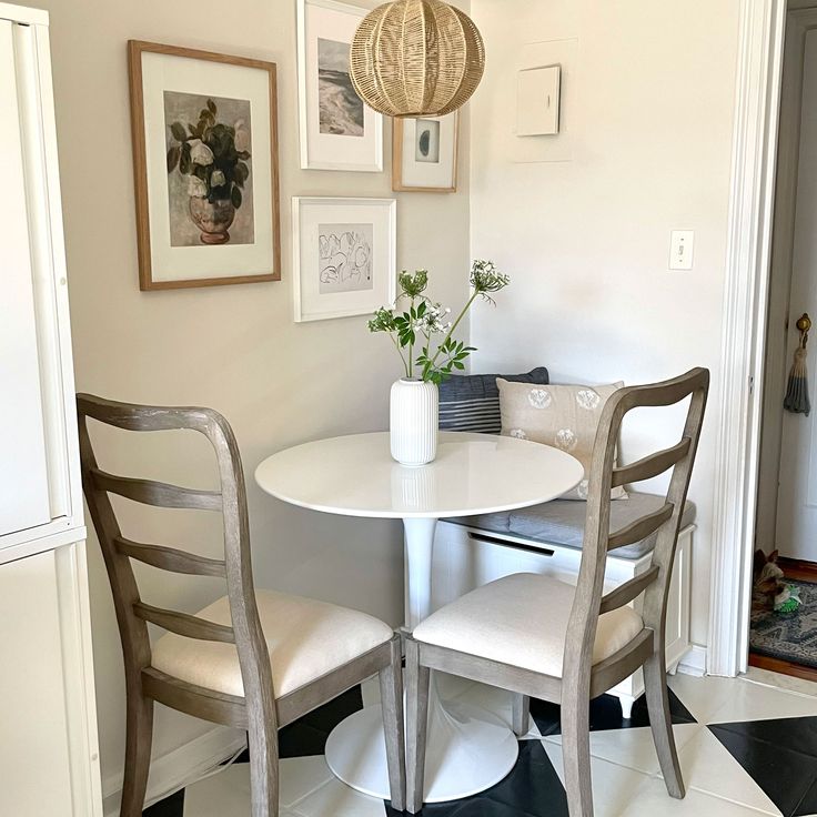 a white table and chairs in a room with pictures on the wall behind it,