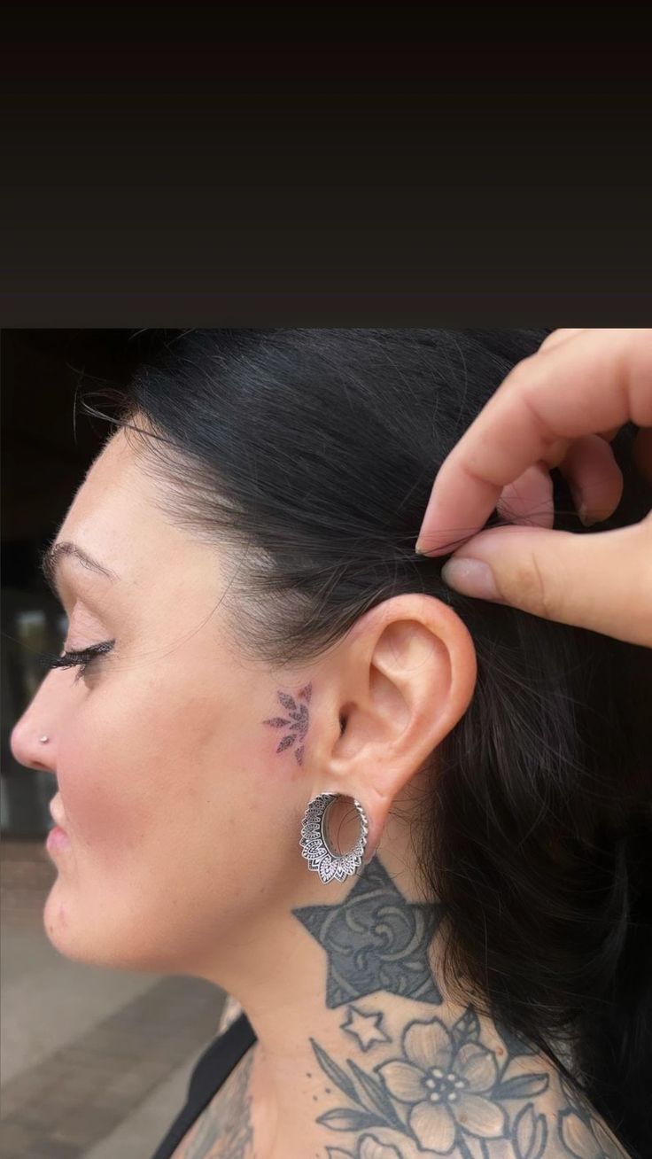 a woman with tattoos on her neck and behind her ear