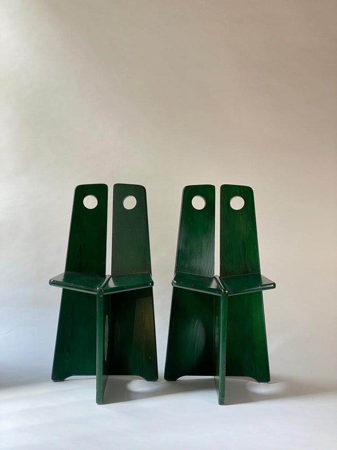 two green chairs sitting next to each other on a white surface in front of a wall