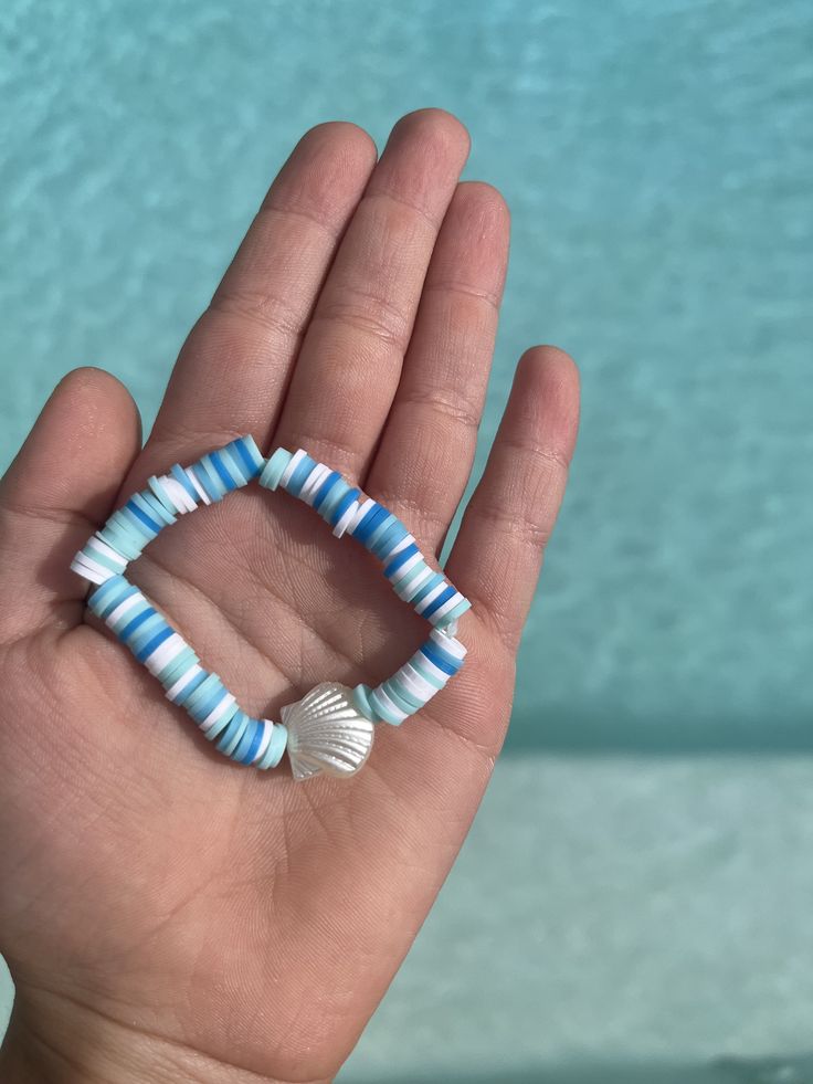 This is a blue bracelet with a seashell bead! Blue Beaded Beachy Jewelry, Blue Round Beads Bracelets For Beach, Blue Bracelets For Summer Beach, Blue Shell-shaped Beachy Jewelry, Handmade Blue Beaded Bracelets For Summer, Coastal Blue Beaded Jewelry, Handmade Blue Jewelry For Beach Season, Shell Beaded Bracelets For Beach Season, Beaded Shell With Ocean-inspired Style For Beach Season