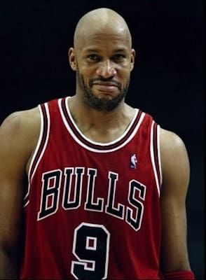 a man in a red jersey is standing with his hands on his hips and looking at the camera