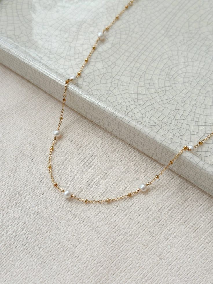 "A Pearl station necklace is a jewelry box staple you will adore for years to come! Each genuine Pearl is hand wrapped in your choice of sensitive skin safe 14K Gold Filled or 925 Sterling Silver. The dainty yet durable beaded chain adds a hint or shimmer to the design.  This versatile chain makes a lovely gift, or a stunning wedding necklace! Pair it with the station Pearl bracelet for a gorgeous matching set. * Choose your length (with adjustable 2\" extender chain) * 15\"+2\" extender or 18\" Delicate Single Strand Jewelry For Anniversary, Dainty Single Strand Jewelry For Anniversary, Delicate Single Strand Necklace For Anniversary, White Gold Single Strand Jewelry As Gift, Delicate Single Strand Jewelry As Gift, 14k Gold Filled Pearl Chain Jewelry For Anniversary, Elegant Yellow Gold Necklace For Wedding Gift, Dainty Necklace With Satellite Chain For Anniversary, Elegant Wedding Necklace With Satellite Chain