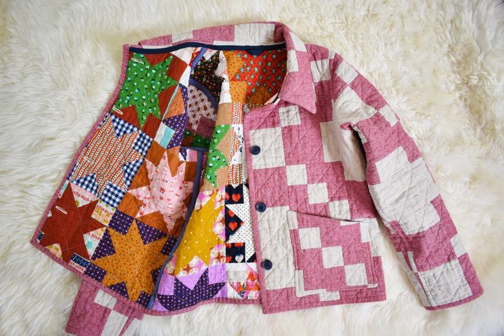 a pink and white quilted jacket laying on top of a rug