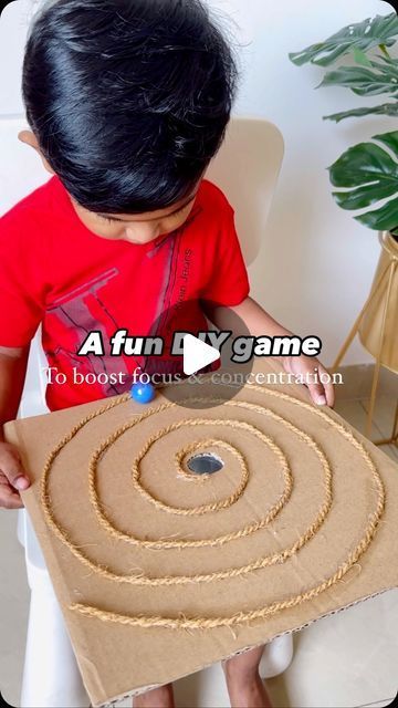 a young boy is playing with a cardboard box that has a spiral design on it