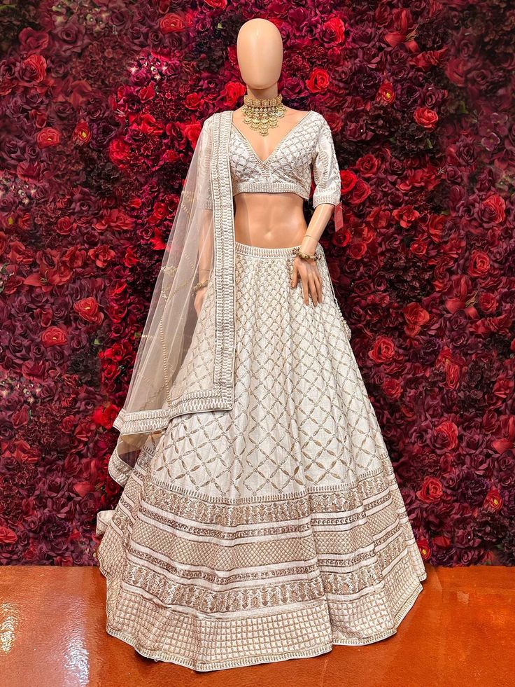 Be your own fashionista with this ivory lehenga. The lehenga is encrusted with very desirable jardozi embroidery and sequins work which is eye catching! Key Features: Color: Ivory Lehenga Fabric: Luxurious silk or similar Embellishments: Intricate silver or gold embroidery or embellishments Silhouette: Flowing and graceful Dupatta: Sheer dupatta with intricate border Designer Cream Lehenga In Dola Silk, Designer Cream Dola Silk Lehenga, Off White Embroidered Choli For Reception, Designer Off White Choli With Intricate Embroidery, Off White Lehenga With Intricate Embroidery For Navratri, Bollywood Style Off White Choli With Resham Embroidery, Designer White Choli With Intricate Embroidery, White Designer Gown With Intricate Embroidery, Designer White Gown With Intricate Embroidery